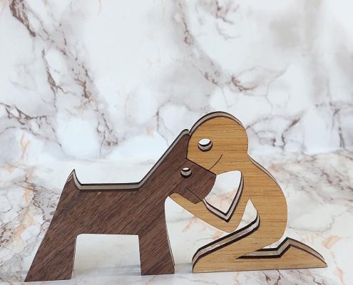 Layered wooden sculpture of sitting man reaching toward walnut dog - handcrafted plywood and walnut bond sculpture