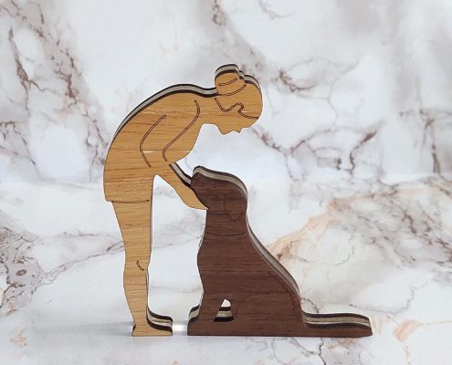 Layered wooden sculpture of woman kneeling with dog reaching up - precision-cut walnut and plywood freestanding decor