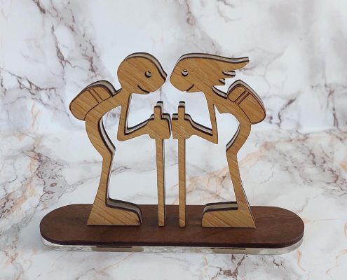 Layered wooden sculpture of Kerry walkers - boy and girl with hiking bags and walking sticks, precision-cut walnut and plywood freestanding decor