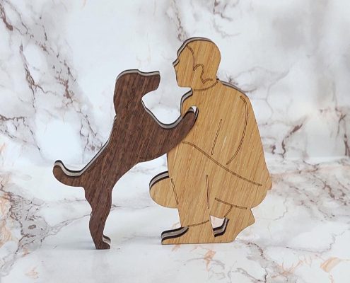 Layered wooden sculpture of a man kneeling with dog jumping up - handcrafted walnut and plywood freestanding decor
