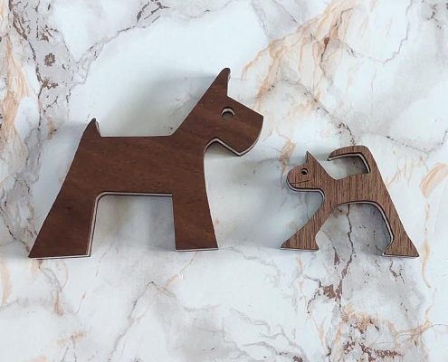 Funny wooden sculpture duo showing tiny cat facing large dog - handcrafted walnut layered pet figurines with humorous size contrast