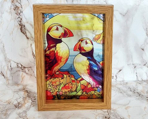 Colorful puffin pair stained glass design sublimated on clear acrylic with vibrant coastal colors in wooden frame for window display