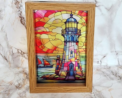 Beautiful lighthouse stained glass effect sublimated on clear acrylic with vibrant sunset colors in wooden frame for window display